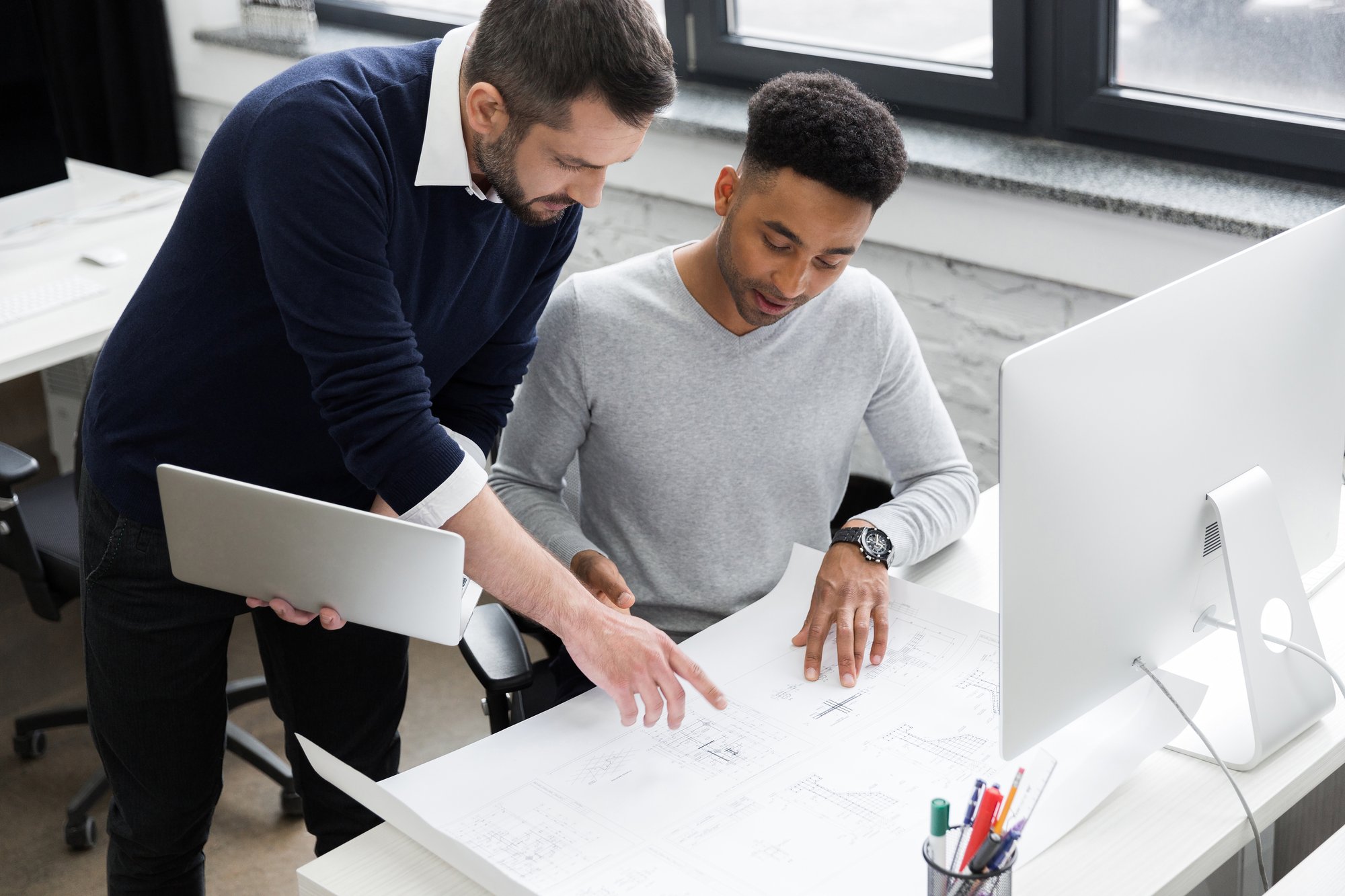 two-smiling-male-office-workers-working-with-laptop